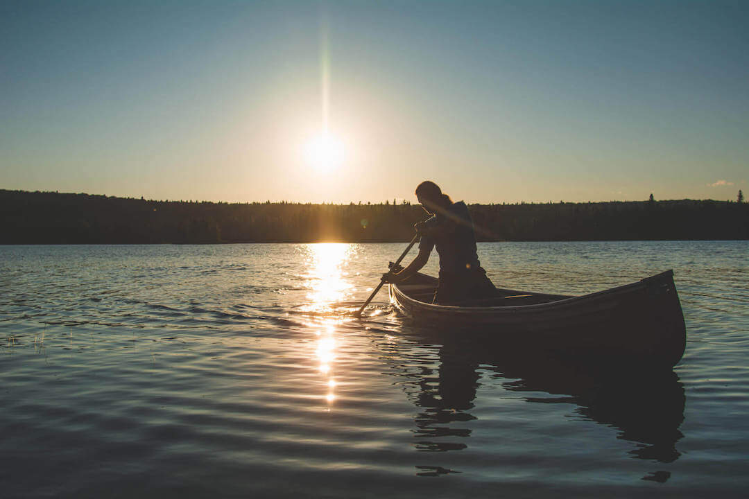 Femme pratiquant le kayak sur un grand lac au crépuscule